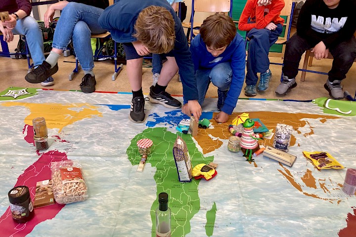 Kinder ordnen fair gehandelte Produkte auf einer großen Weltkarte zu.